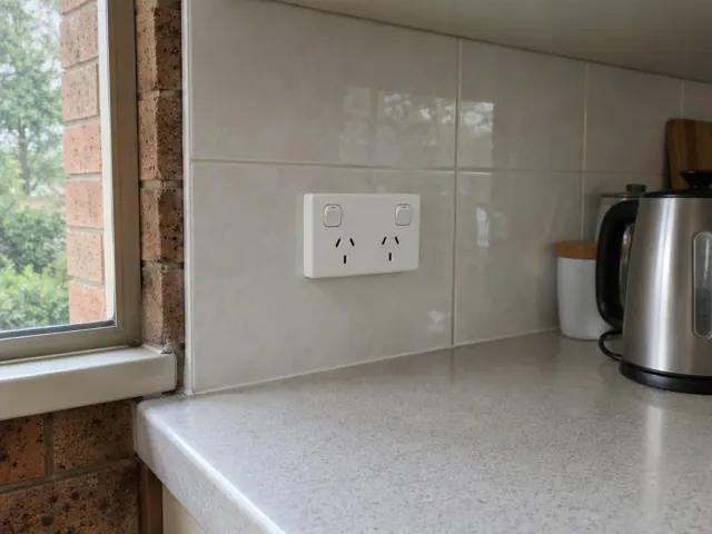 Double power point on tiled kitchen splashback above a stone benchtop in Winston Hills