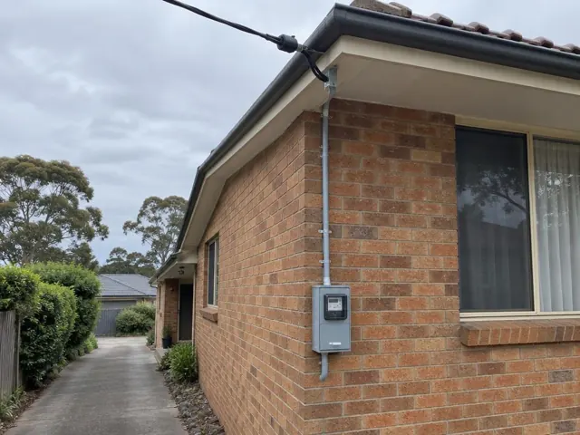 Brick house corner with overhead service cable and meter box on the wall in Bella Vista